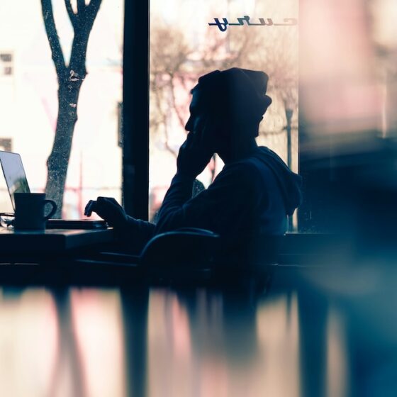 silhouette of a guy using a computer in a coffeeshop