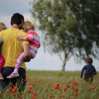 Father with 3 kids in a field.