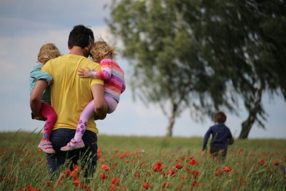 Father with 3 kids in a field.