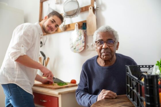 Guy cooking dinner for elderly gentlemen.