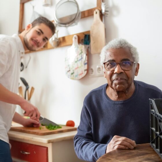 Guy cooking dinner for elderly gentlemen.