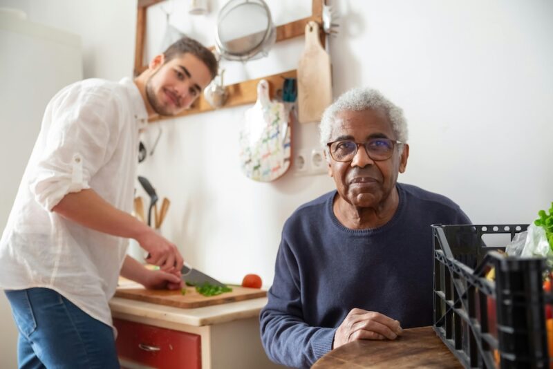 Guy cooking dinner for elderly gentlemen.