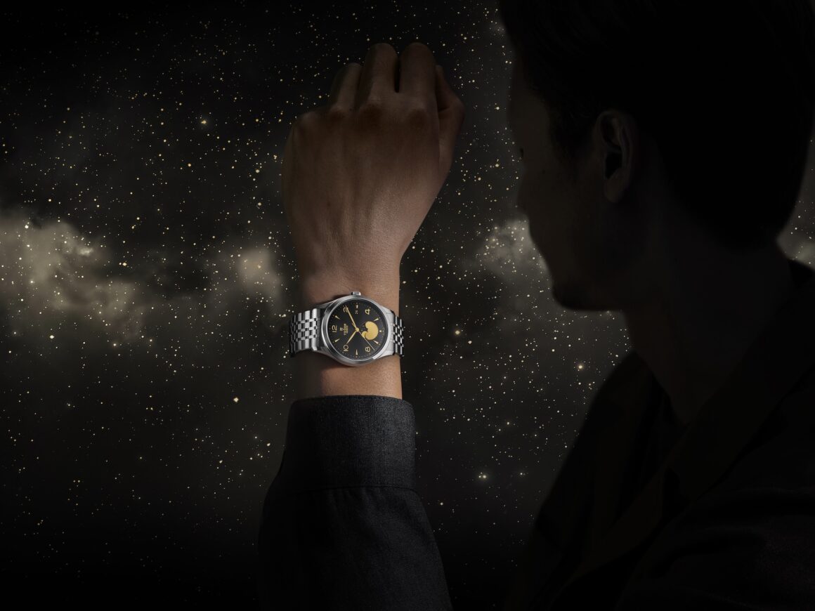 Lifestyle editorial shot — the TUDOR Luna 1962 peeking under a cuff, worn with a suit. Closes the story with aspiration and real-world wearability, linking it back to modern masculinity.